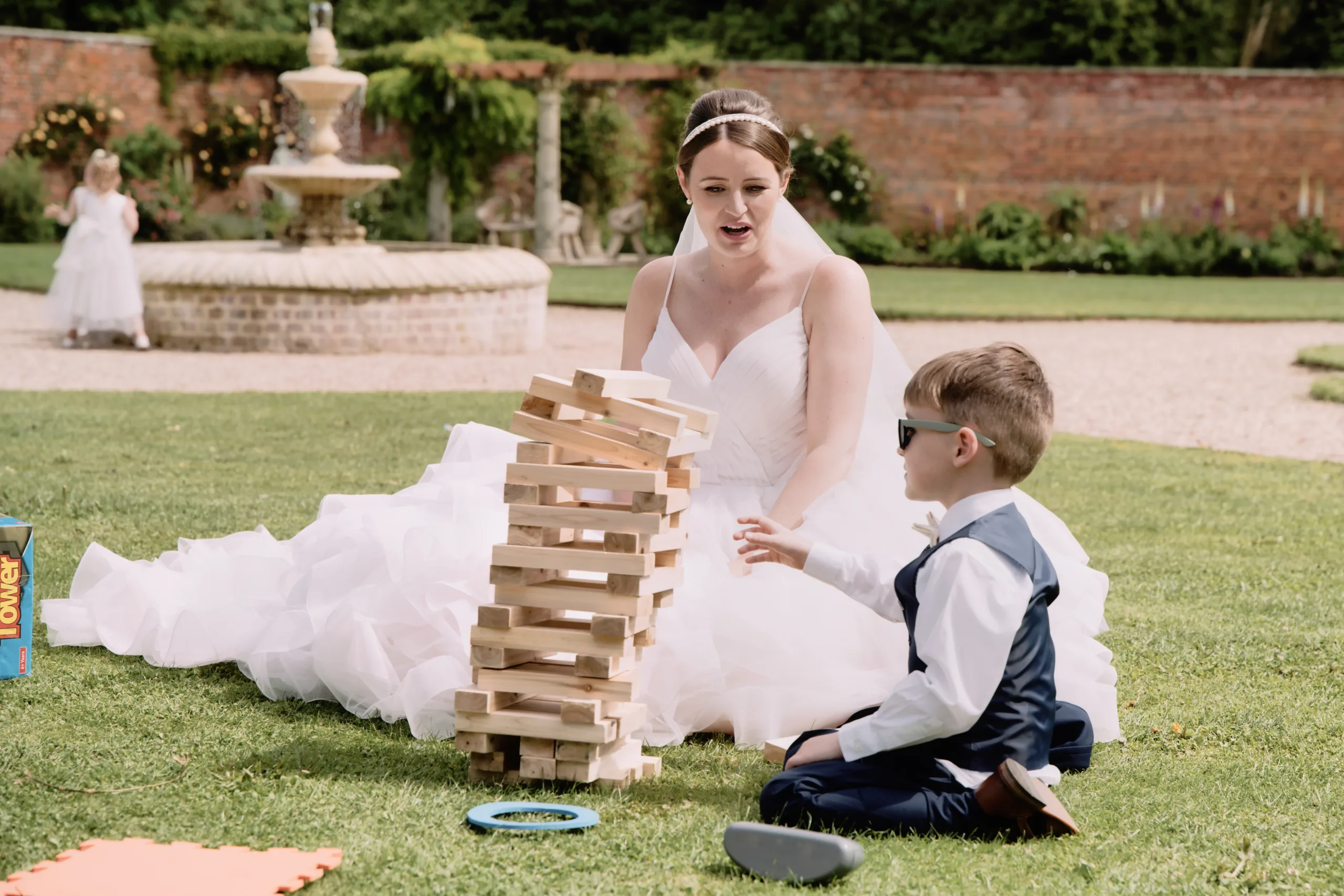 a bride and a boy playing with a tower of blocks.