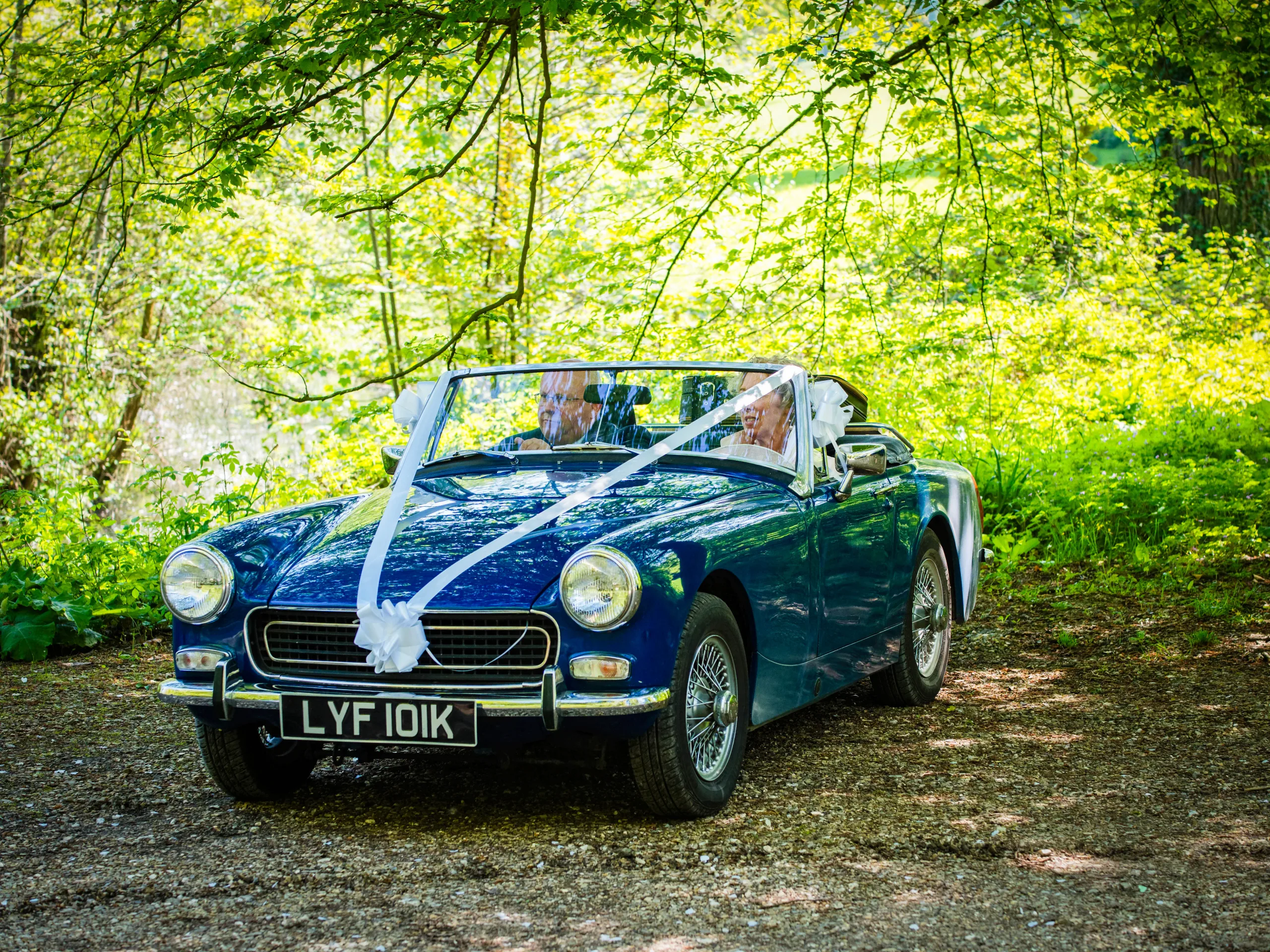 a bride and groom in a blue sports car.