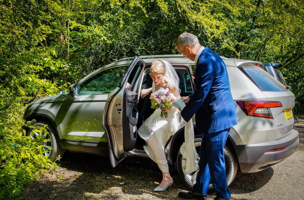 A bride and groom, captured by the skilled Wedding Photographer at Orchardleigh, gracefully stepping out of a car.