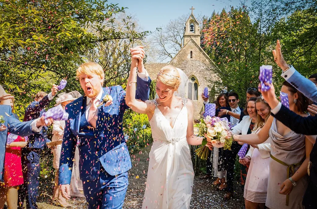 St Marys Church Orchardleigh Estate :a bride and groom walk through confetti thrown by guests.