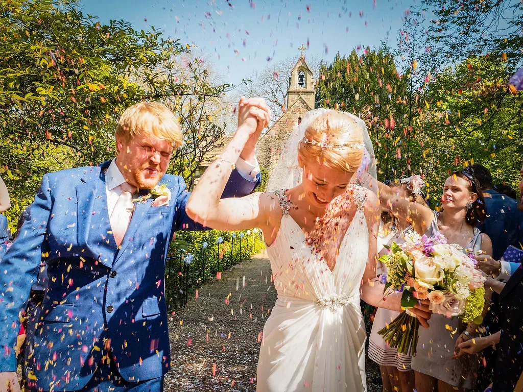 We got married at Orchardleigh: a bride and groom walking through confetti.