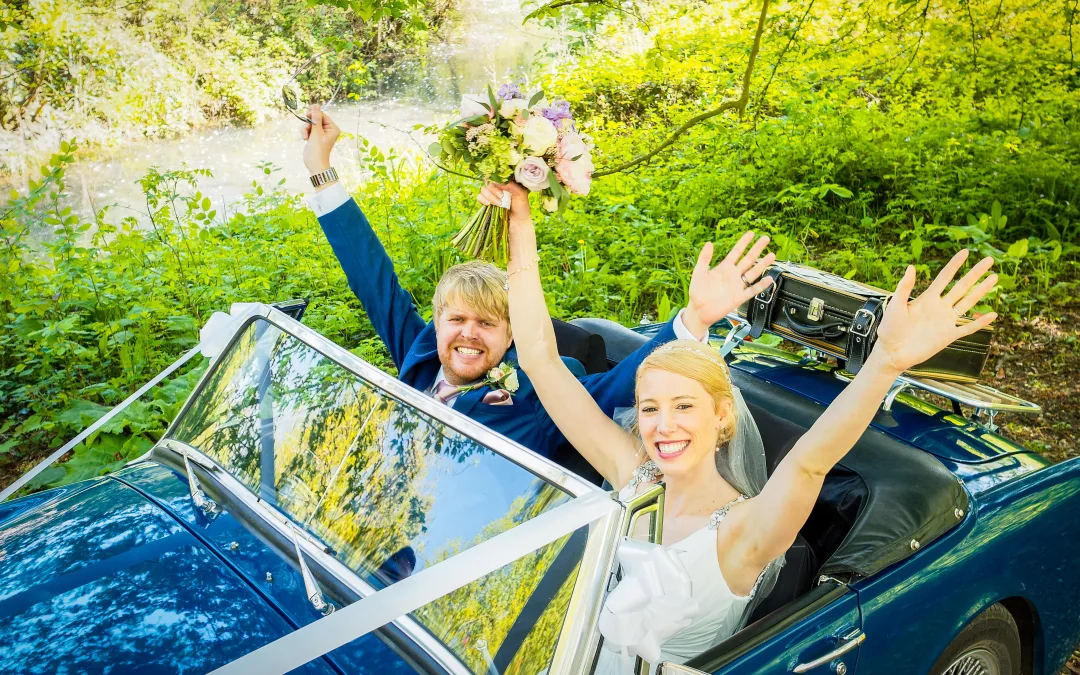 a bride and groom sitting in a convertible car.