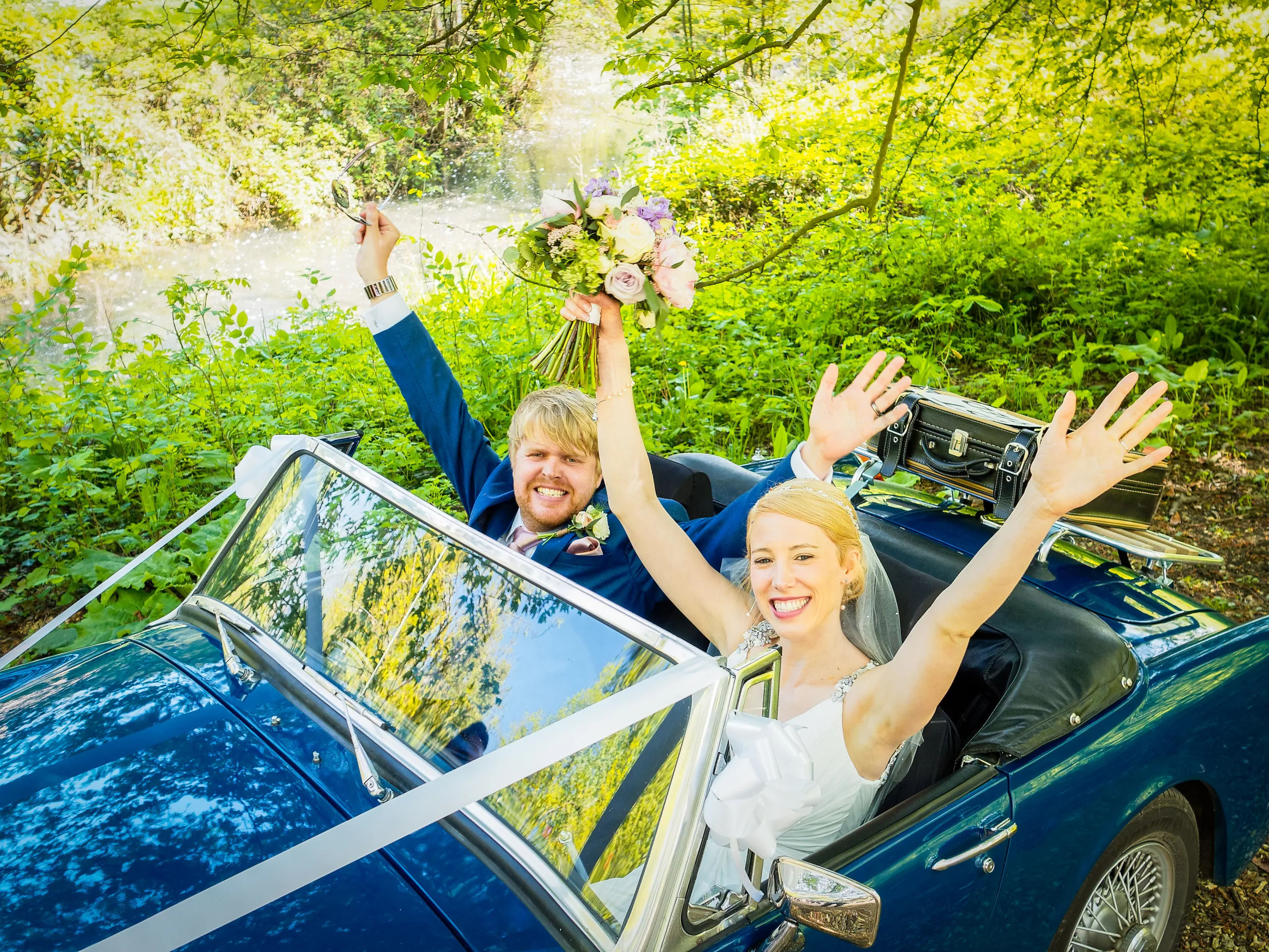 a bride and groom sitting in a convertible car.