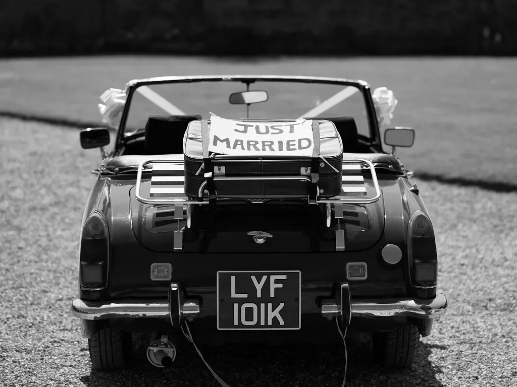 a black and white photo of a convertible car with a just married sign on the.