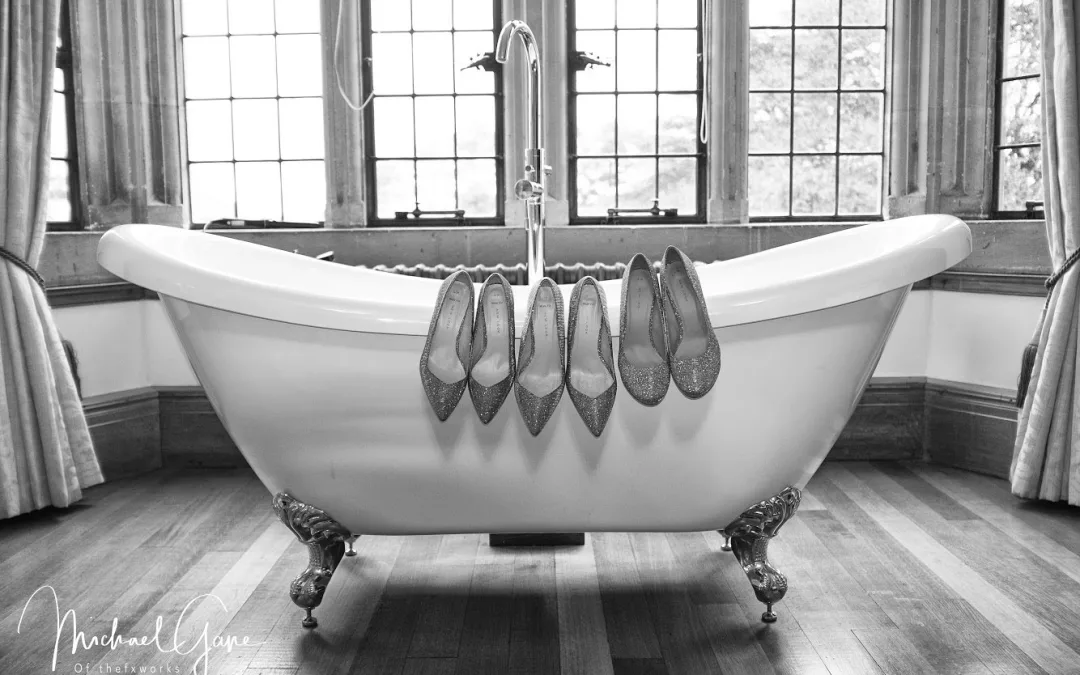 A Coombe lodge bath tub with five pairs of shoes hanging from the claw foot side.