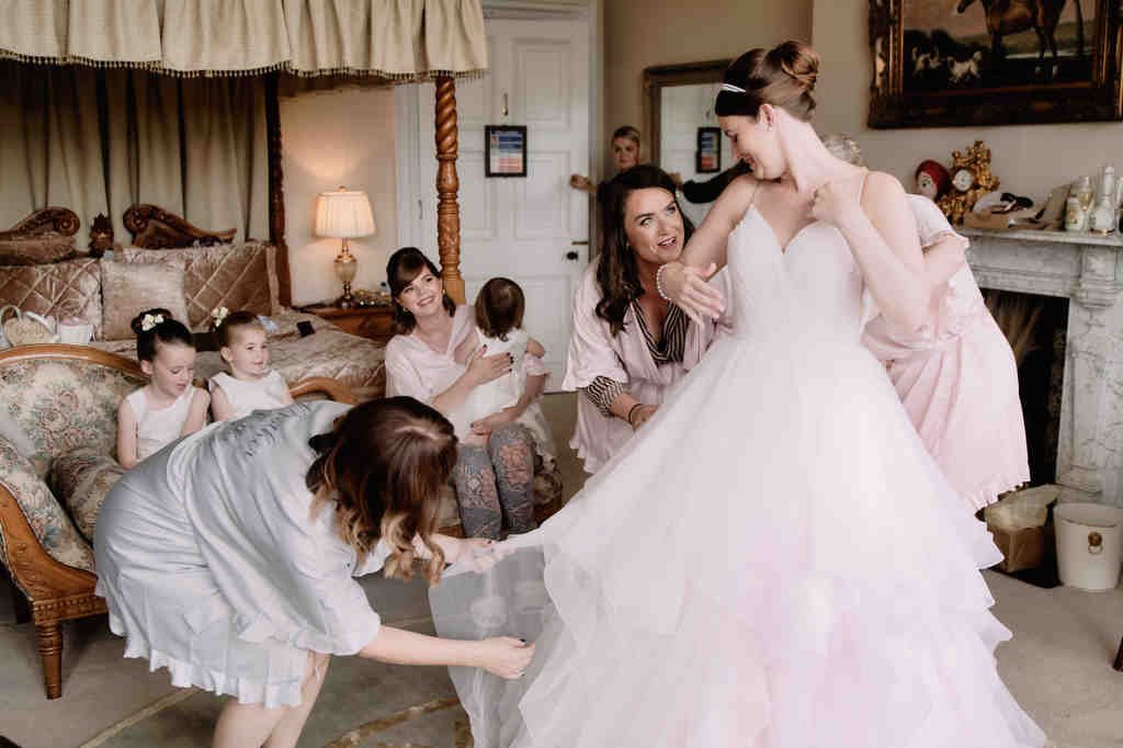 a woman in a wedding dress is trying to get into a dress.