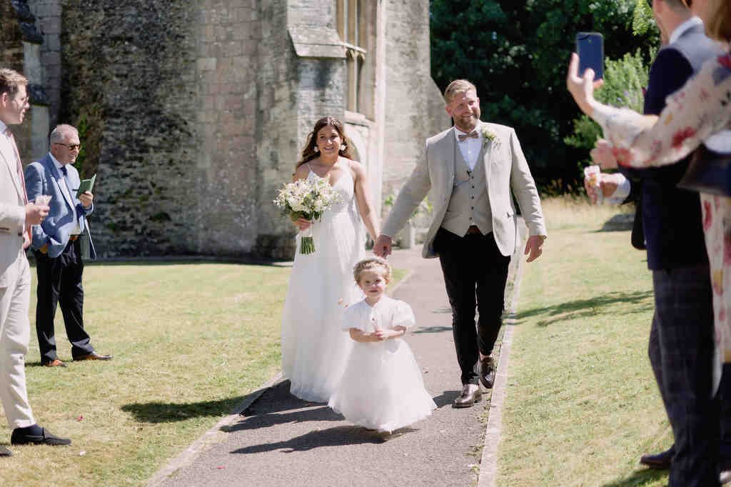 Seymours Court Frome: a bride and groom walking down a path with their flower girl.