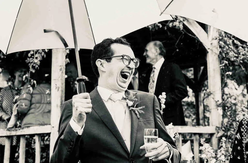 Reportage Wedding Photography in the City of Bath: a man in a suit holding an umbrella.