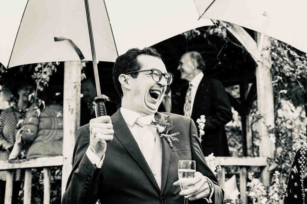 Reportage Wedding Photography in the City of Bath: a man in a suit holding an umbrella.
