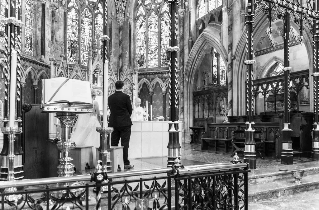 Photographer and his view: a black and white photo of a man standing in a church.