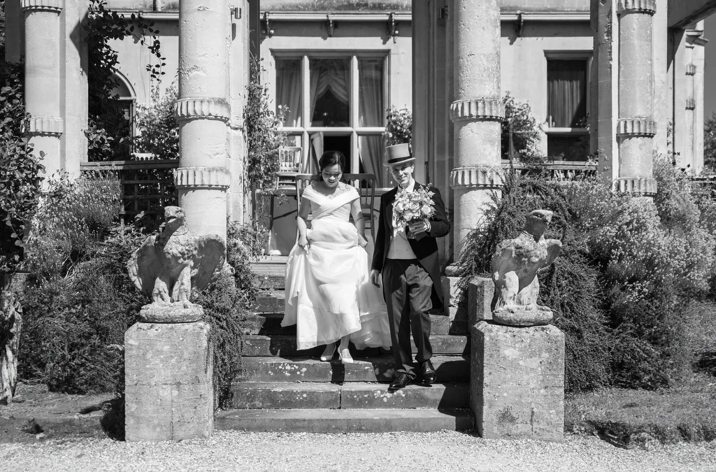 Orchardleigh House a :bride and groom walking down the steps of a mansion.