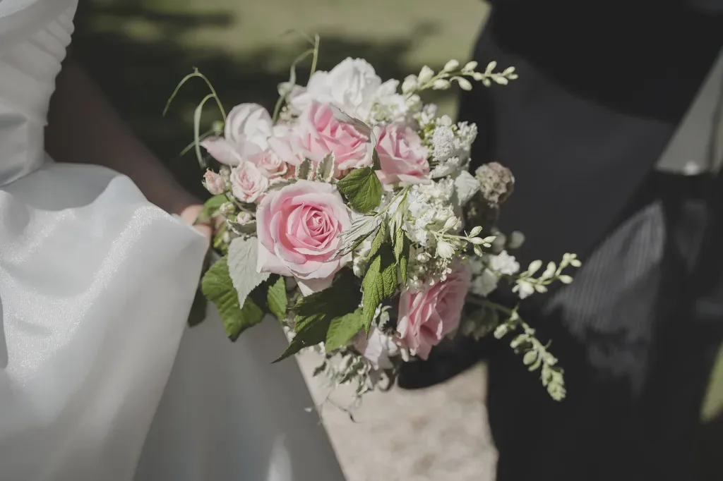 Orchardleigh Weddings: a bride and groom holding a bouquet of pink and white roses.