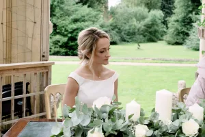 A Castle Combe Manor wedding photographer captured a mesmerizing shot of a bride and groom sitting at a table adorned with beautiful candles.