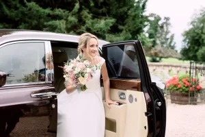 A bride getting out of a Rolls Royce car in Castle Combe.