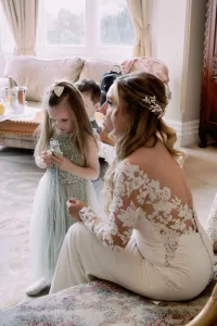 A beautiful bride and her adorable flower girl are gracefully posing on a luxurious couch during their enchanting Orchardleigh House wedding, captured by a skilled photographer.