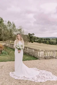 A bride in a lace wedding dress standing in front of a Orchardleigh House.
