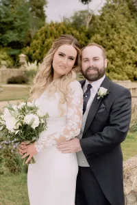 A bride and groom posing in front of a stone wall captured by an Orchardleigh House Wedding Photographer.