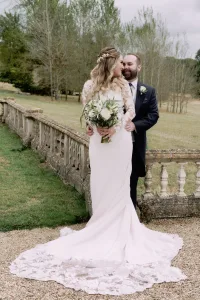 A bride and groom posing for a photo in front of a stone wall captured by Orchardleigh House Wedding Photographer.