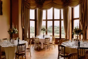 A large room at Orchardleigh House with tables and chairs set up for a wedding reception.