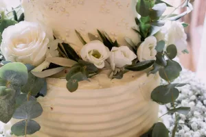 A wedding cake adorned with elegant white flowers and eucalyptus, captured beautifully by an Orchardleigh House Wedding Photographer