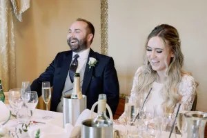 Orchardleigh House Wedding Photographer captures a bride and groom laughing at a table.