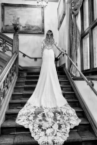 A bride is gracefully descending the stairs at Orchardleigh House, adorned in her exquisite wedding dress, while beautifully captured by a professional wedding photographer.