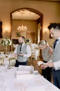A group of people standing around a table in a large room, captured by an Orchardleigh House Wedding Photographer.