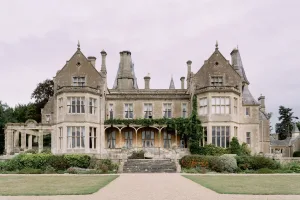 A grand mansion amidst a lush grassy field, perfect for Orchardleigh House Wedding Photographer to capture timeless moments.