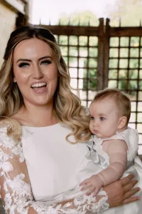 A woman in a white dress holding a baby, captured by an Orchardleigh House wedding photographer.