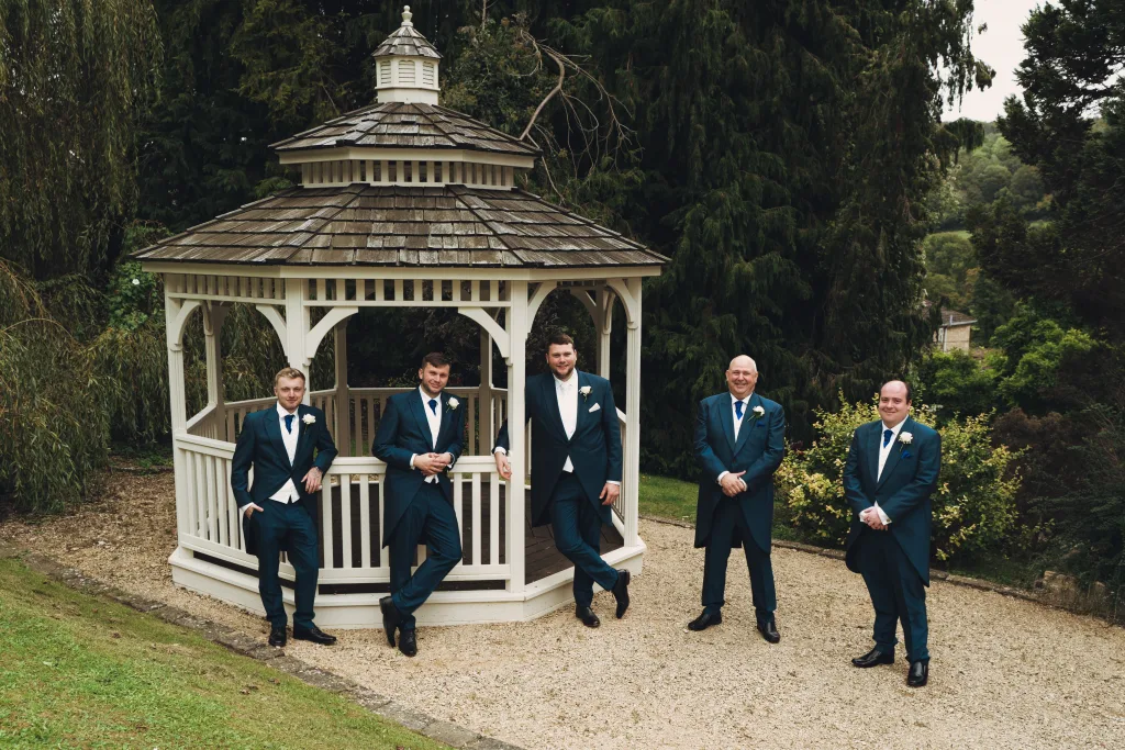 A group of groomsmen standing in front of a gazebo. Limply Stoke Hotel Wedding Photographer