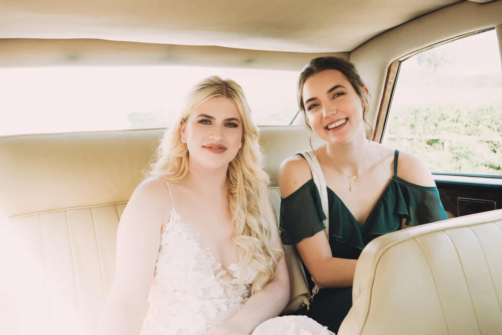 Two brides sitting in the back seat of a car. Priston Mill Wedding Photographer