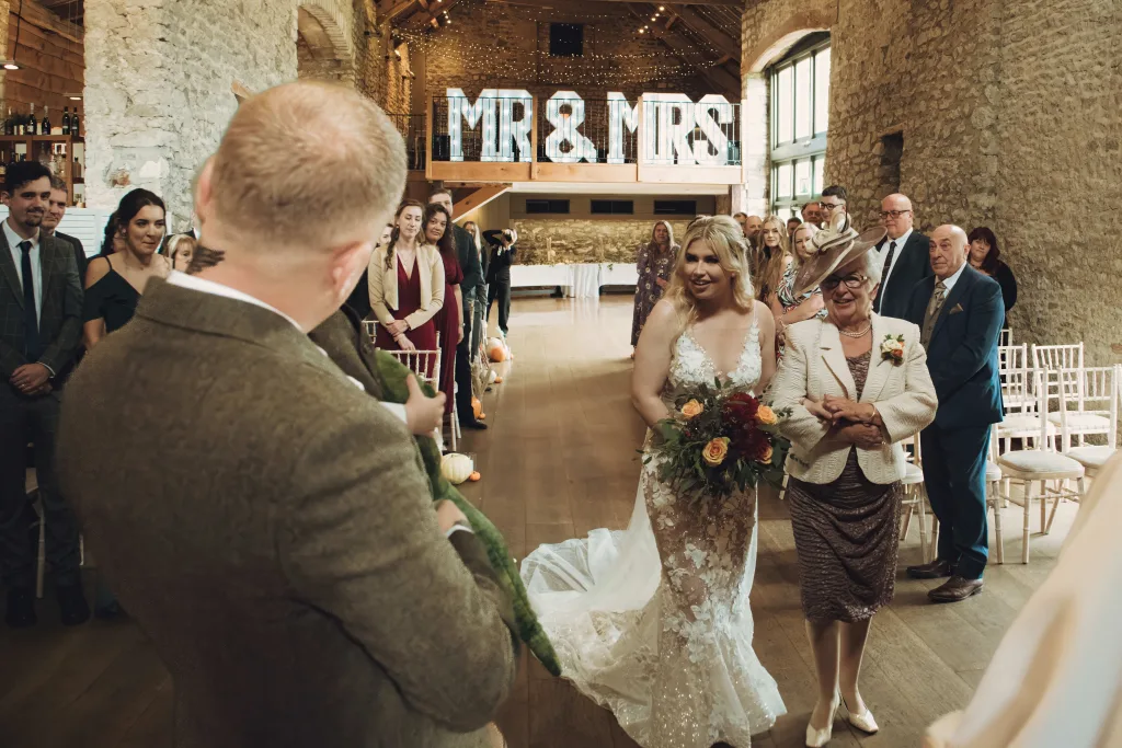 A bride and groom walking down the aisle in a barn at Priston Mill taken by Michael Gane