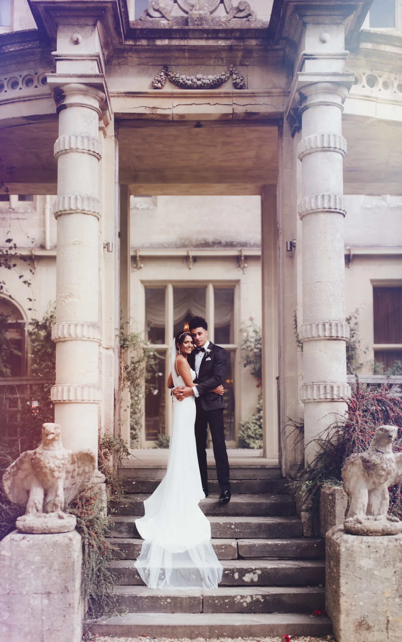 A bride and groom posing on the steps of an ornate building. Orchardleigh House Wedding Photographer