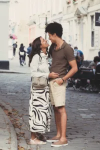 A couple gazes at each other affectionately on a quaint city street during their complimentary engagement photo shoot.
