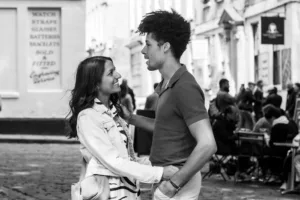 Two people share a moment of affection on a city street during their complimentary engagement photo shoot.