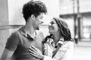 A smiling man and woman looking at each other affectionately during their complimentary engagement photo shoot.