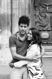 Two people embracing and smiling during their complimentary engagement photo shoot in front of an ornate door.