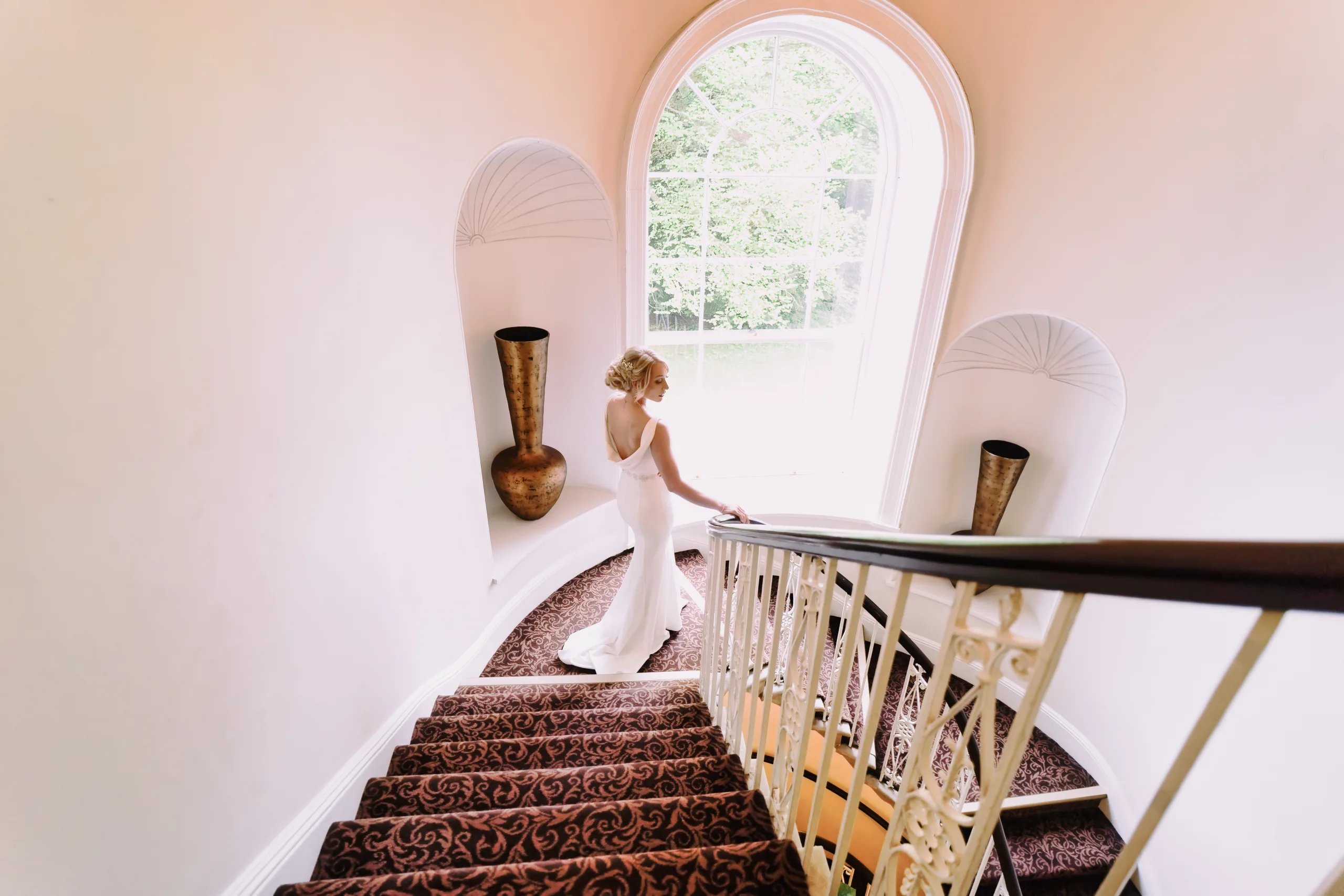 A bride walking down the stairs in a wedding dress. Wedding Photographer Bath
