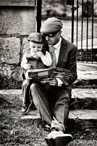 A man in a suit reading a book to his son during a wedding at Orchardleigh.