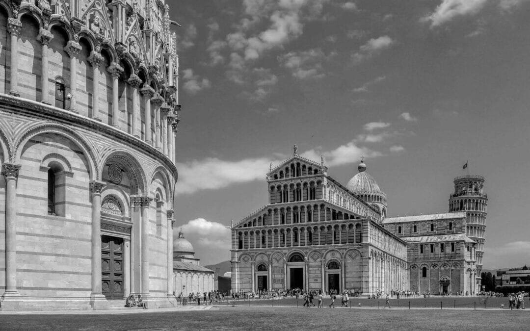 Black & White Film Photography captures Pisa’s Cathedral Square, featuring the Baptistery, the Cathedral, and the Leaning Tower beneath a partly cloudy sky.