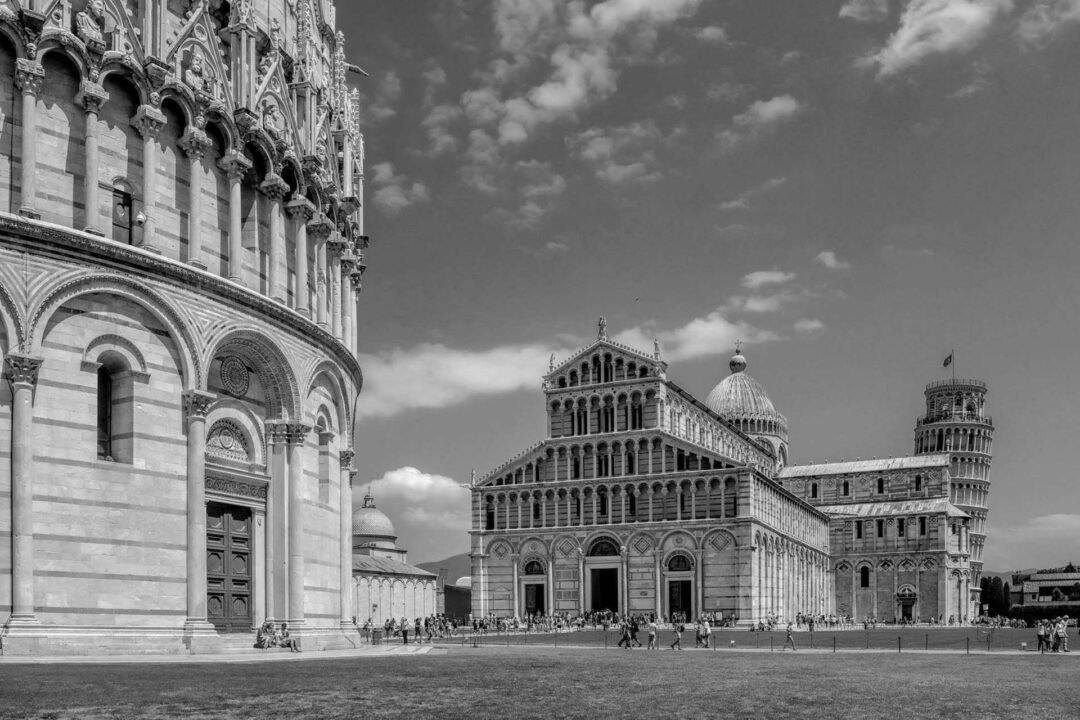 Black & White Film Photography captures Pisa’s Cathedral Square, featuring the Baptistery, the Cathedral, and the Leaning Tower beneath a partly cloudy sky.