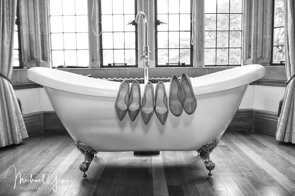 A black and white photo of a bathtub with shoes on it at Coombe Lodge Wedding Venue and Widbrook grange