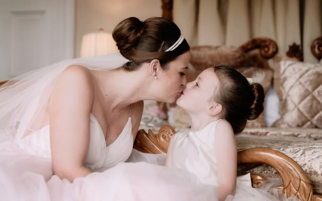 A bride and flower girl kissing at Orchardleigh House, captured by a talented wedding photographer.