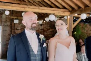 A bride and groom, captured by a Orchardleigh House Wedding Photographer, strolling down the aisle at a barn wedding.