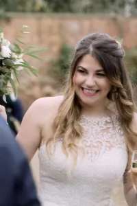 A bride smiles as she holds a glass of wine during her Orchardleigh House wedding.