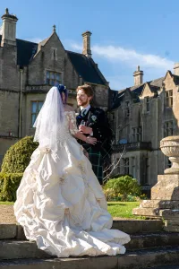 An Orchardleigh House wedding photographer captures the beautiful moment of a bride and groom posing in front of a castle.