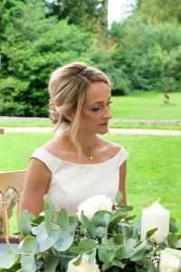 An enchanting scene unfolds as a graceful bride and dashing groom share an intimate moment at a beautifully adorned table in the midst of a picturesque garden. With the serene ambiance provided by Orchardleigh