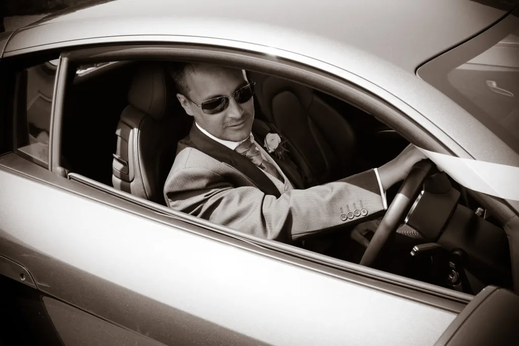 A man wearing sunglasses driving a sports car in St. Andrie's park Wedding Photographer
