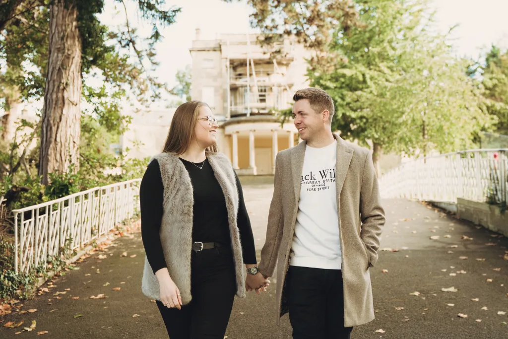 A couple holding hands in front of a mansion. Engagement Photo-Shoot in Bath UK