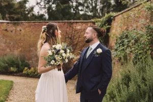 A wedding photographer capturing a bride and groom in front of a brick wall at Bath.